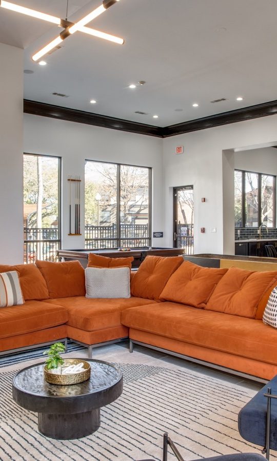 a living room with orange couches and a large window at The  Vincent