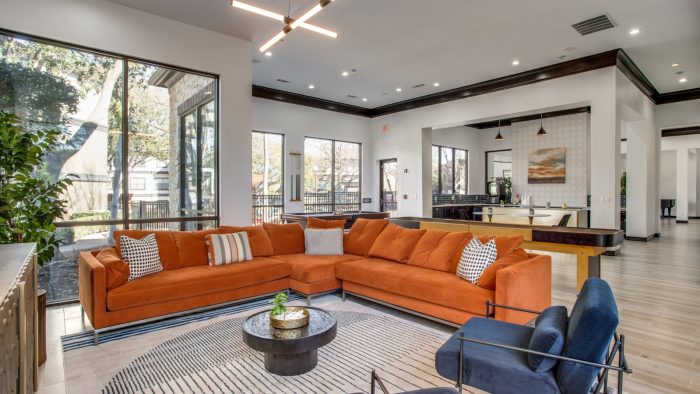 a living room with orange couches and a large window at The  Vincent